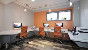A room with orange walls and a desk with a computer and a monitor.